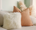 Natural white sheepskin cushion with linen cushions on a sofa