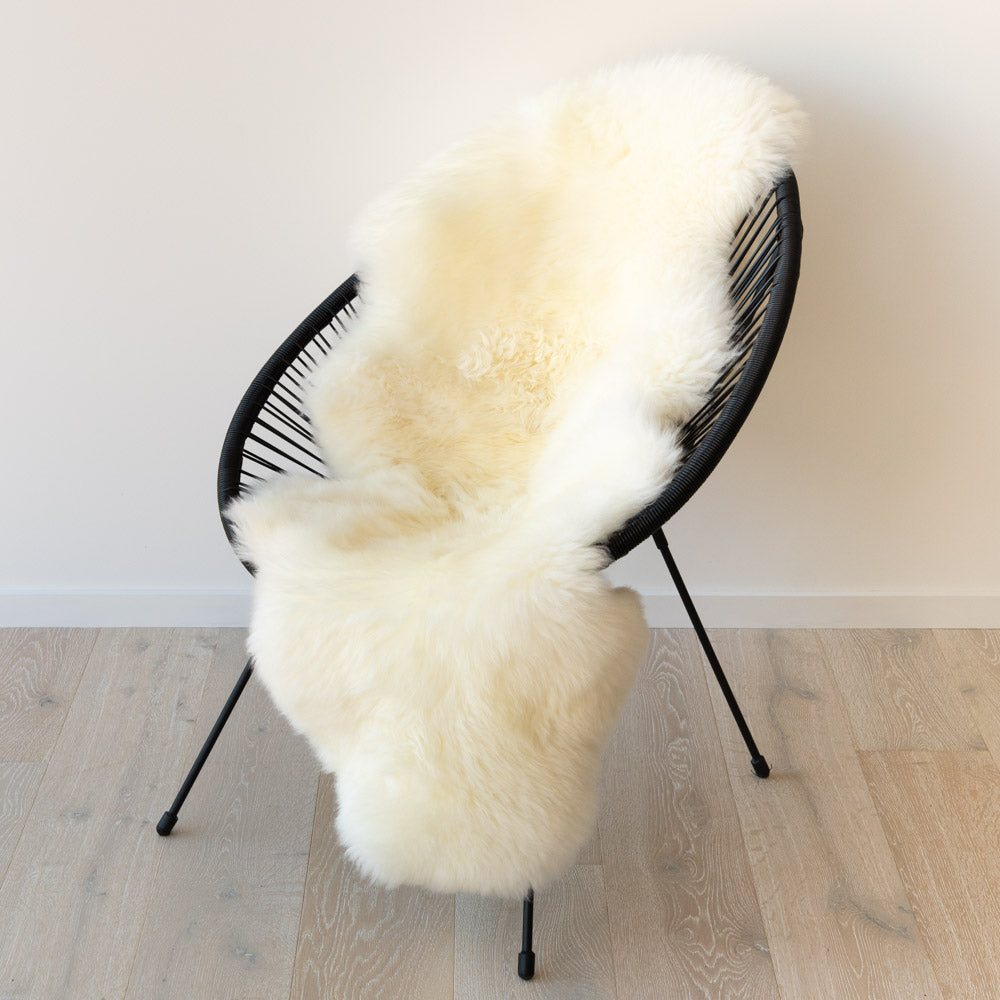 Natural white double sheepskin rug over a black chair
