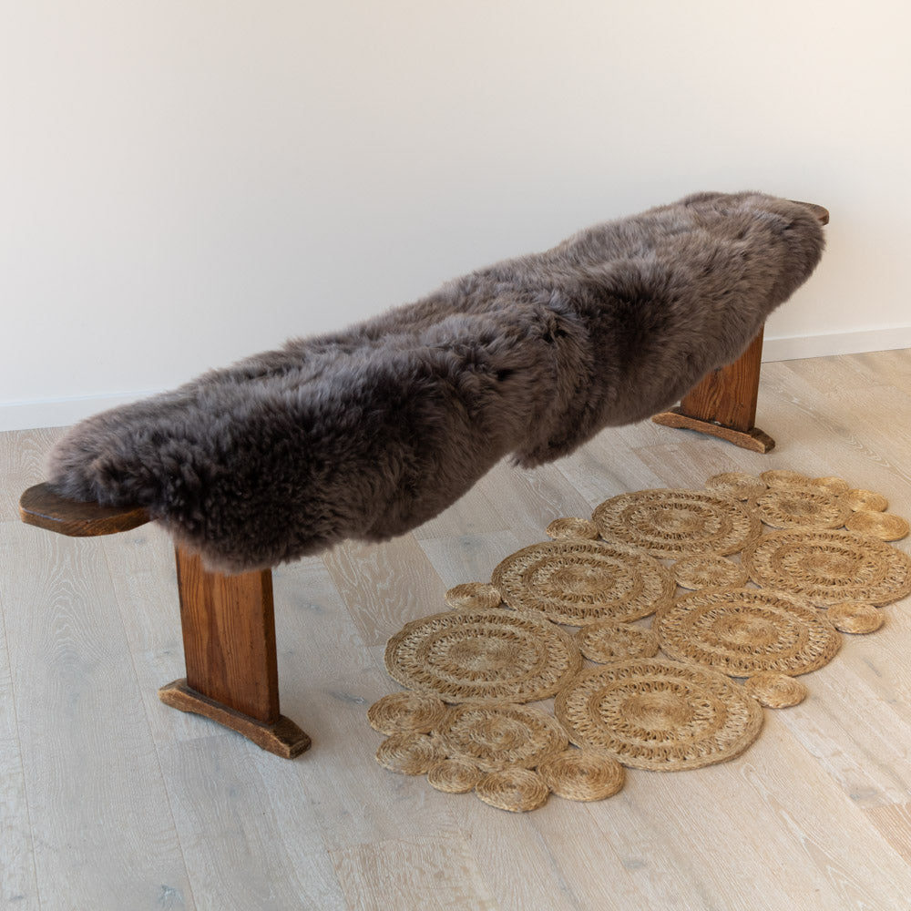 Chocolate double sheepskin rug over a wooden bench