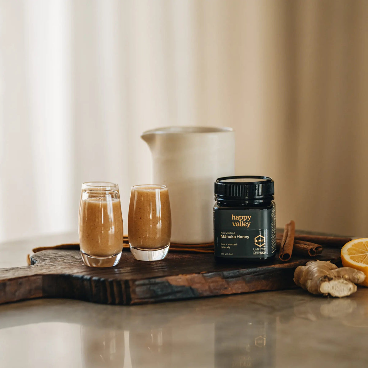 Happy Valley Mānuka Honey UMF 15+ jar with two drinks on a wooden board