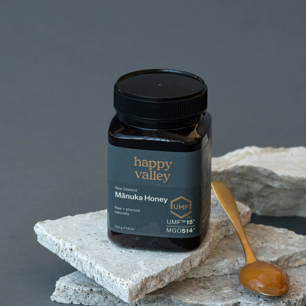 Happy Valley Mānuka Honey UMF 15+ jar on stone with a wooden spoon