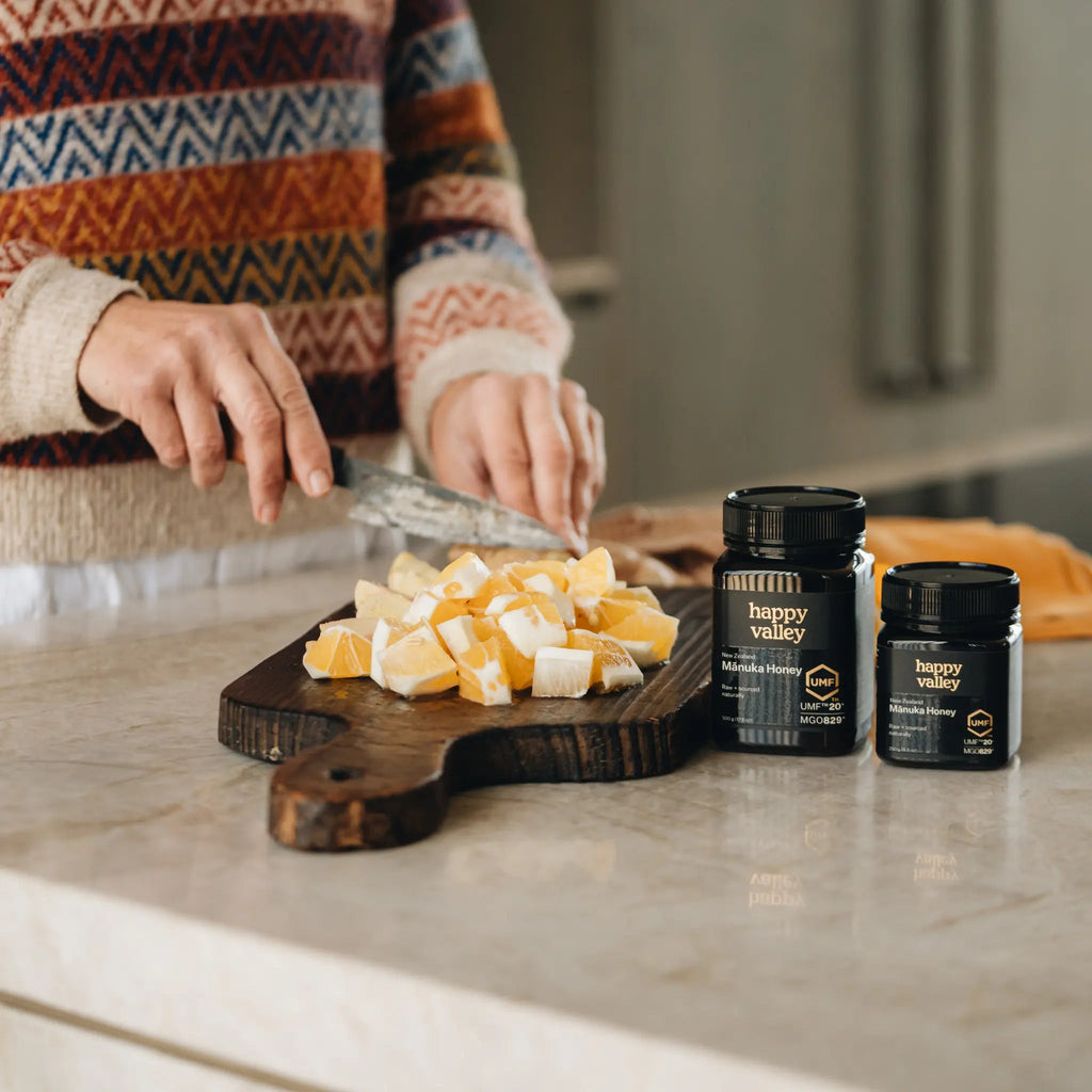Happy Valley Mānuka Honey jars on a bench with chopped ginger