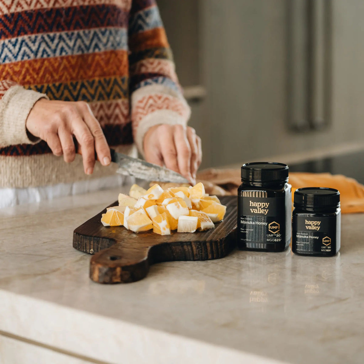 Happy Valley Mānuka Honey jars on a bench with chopped ginger