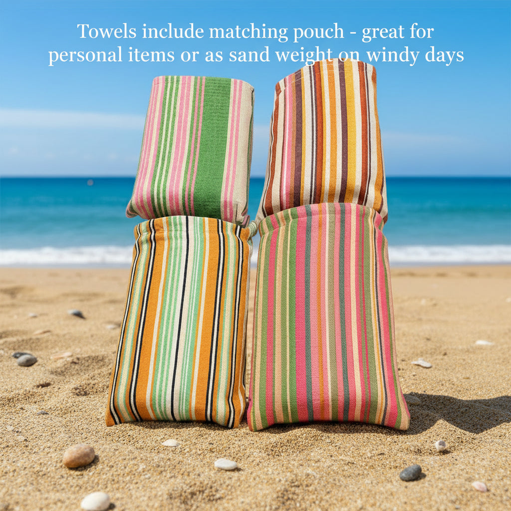 Four rolled Frankly Cotton beach towels with matching pouches on the beach