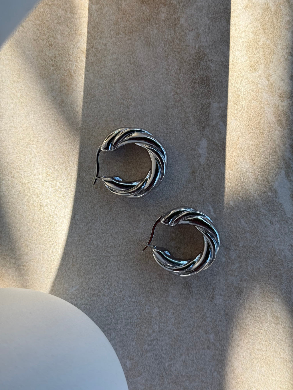 Tāwhirowhiro Silver Twisted Hoop Earrings in sunlight