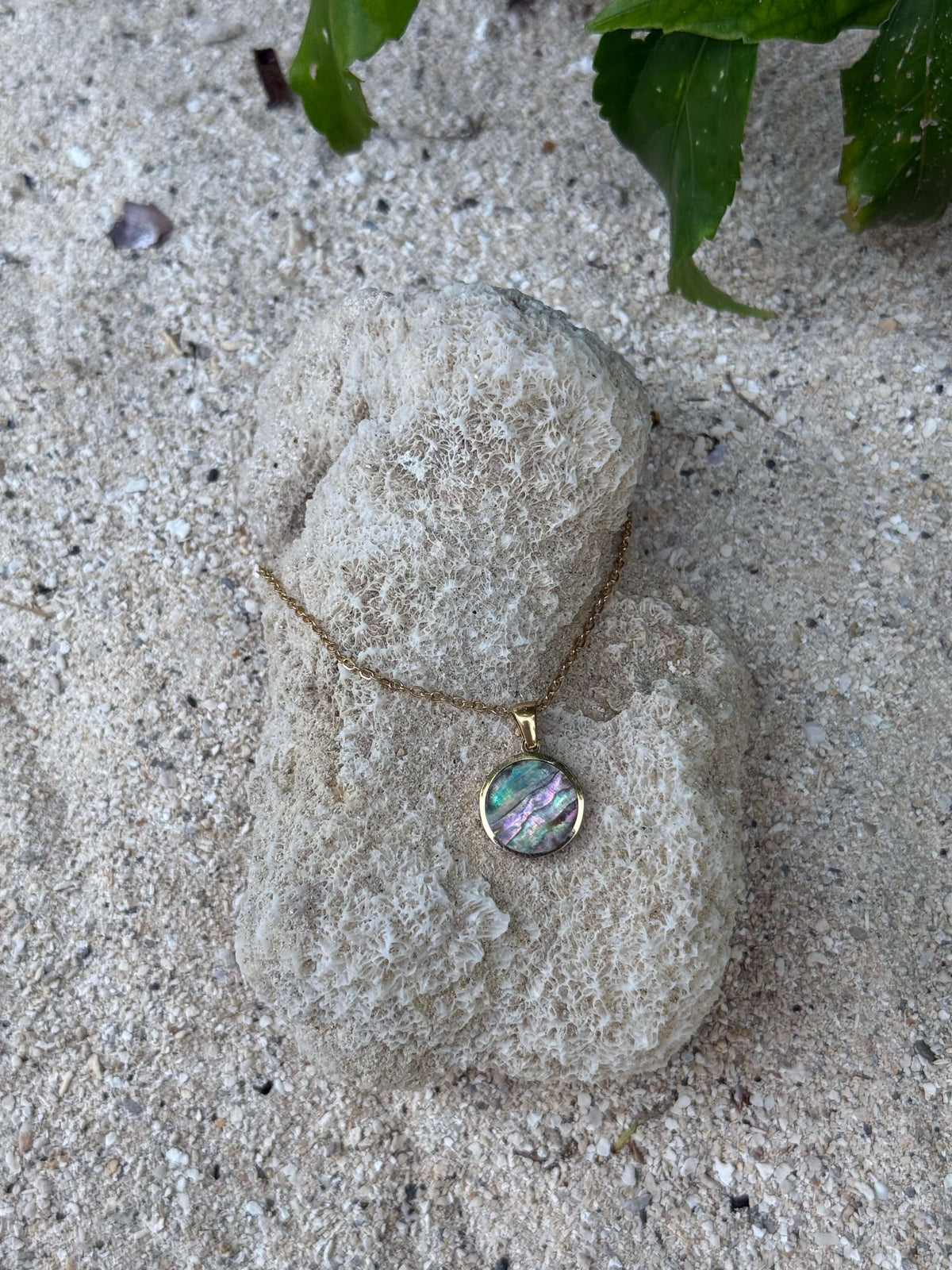 Pītau Moana Set pāua necklace and earrings on a stone, close view