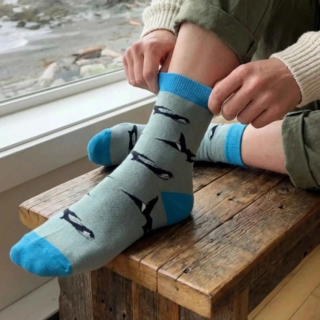 Person pulling on blue-grey Barekind orca socks