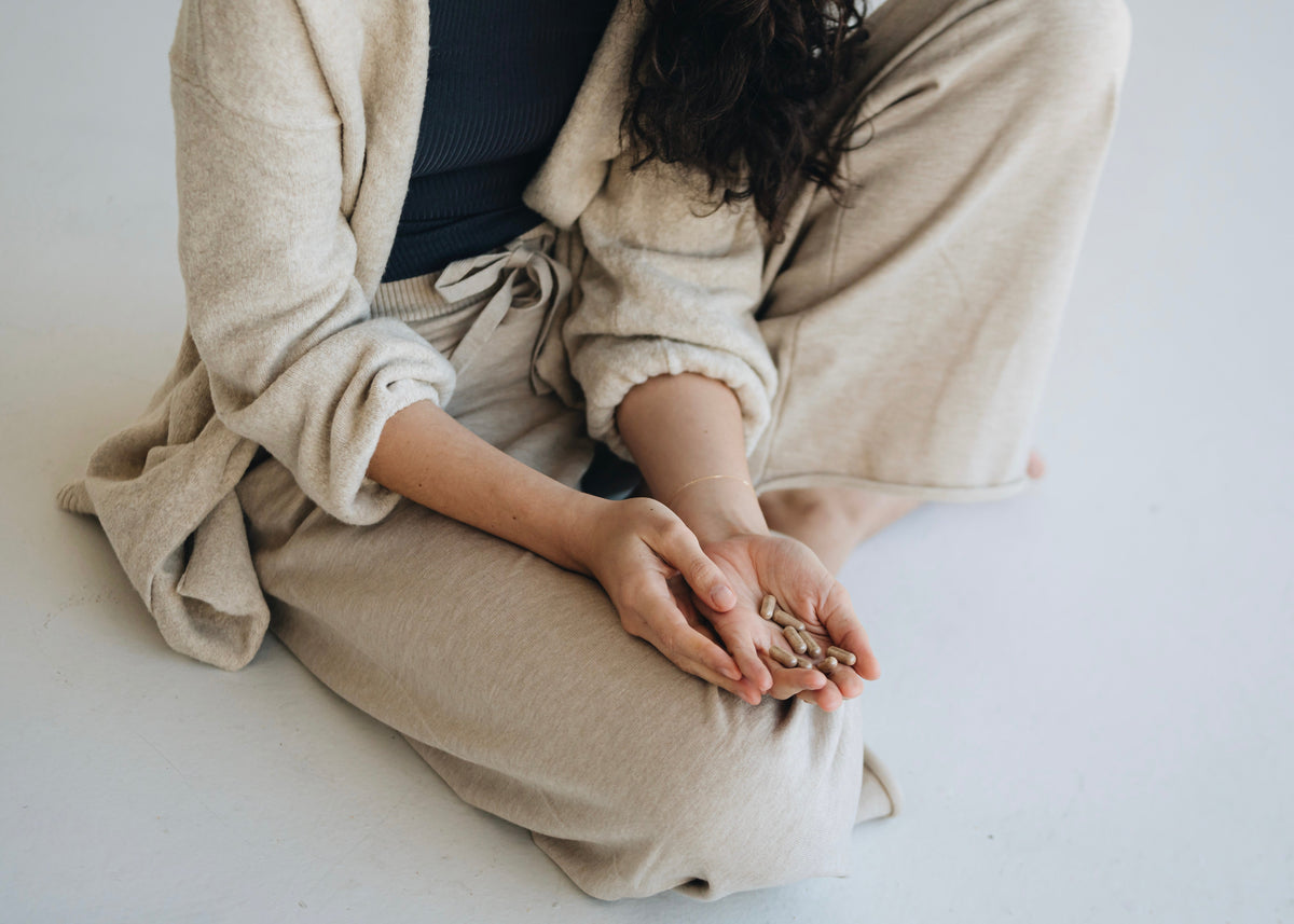 Person sitting cross-legged holding bee pollen capsules