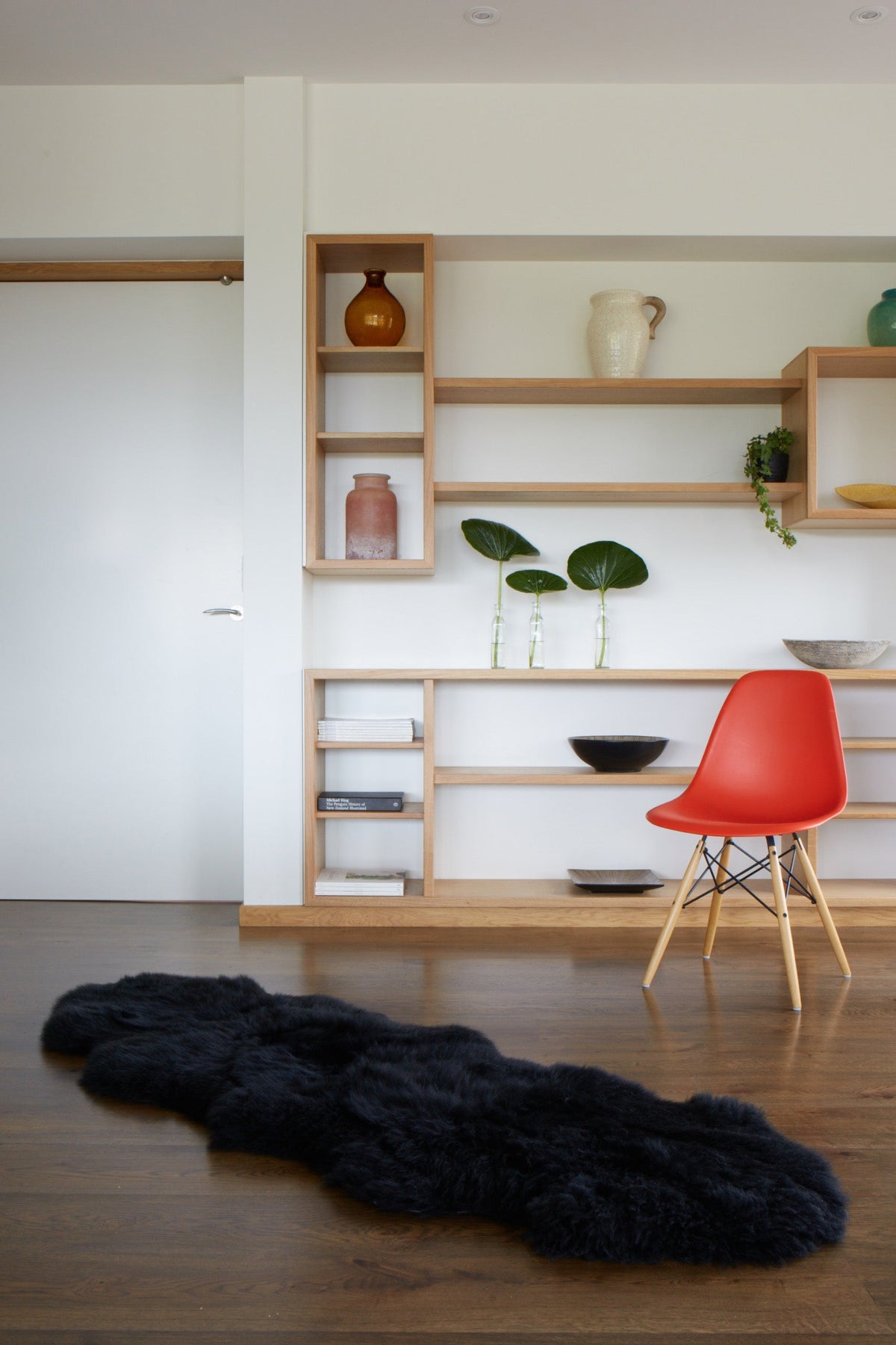 Black double sheepskin rug on a wooden floor