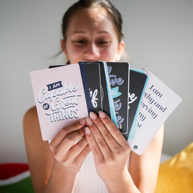 Girl holding a fan of Positive Affirmations cards