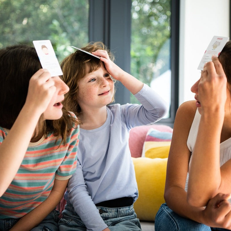 Children playing Emotional Warriors, holding cards to their foreheads