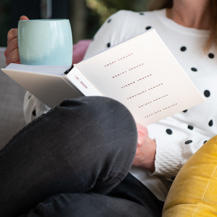 Person reading an I Am... Mindset Journal with a mug