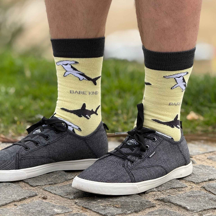 Person in grey sneakers wearing yellow Barekind shark socks