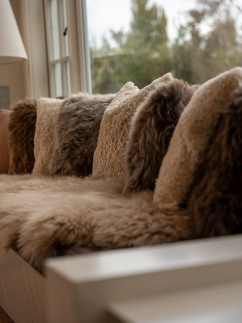 Classic Sheepskins cushions on a window seat with a sheepskin rug