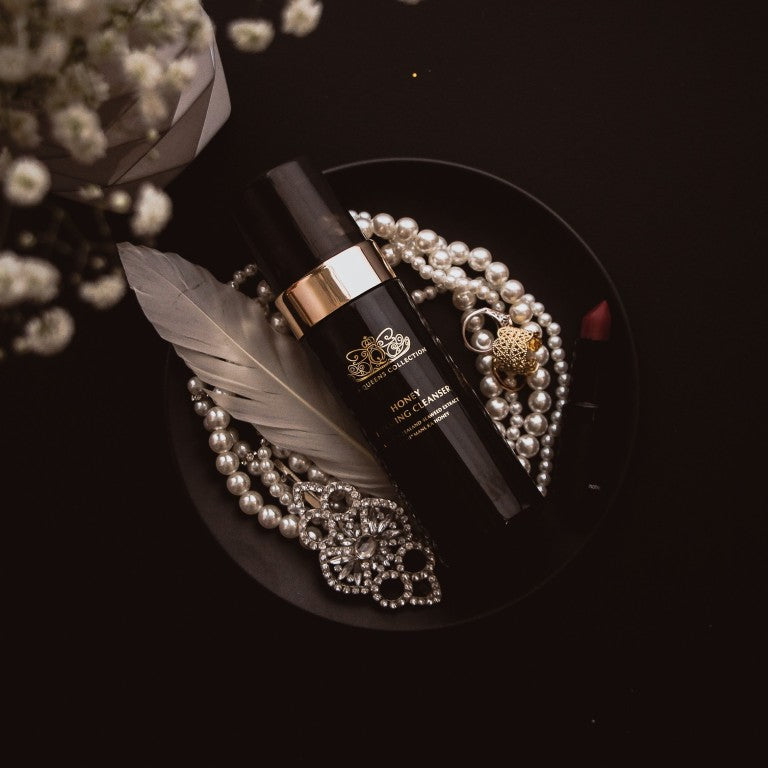 Honey Foaming Cleanser bottle on a black plate with pearls