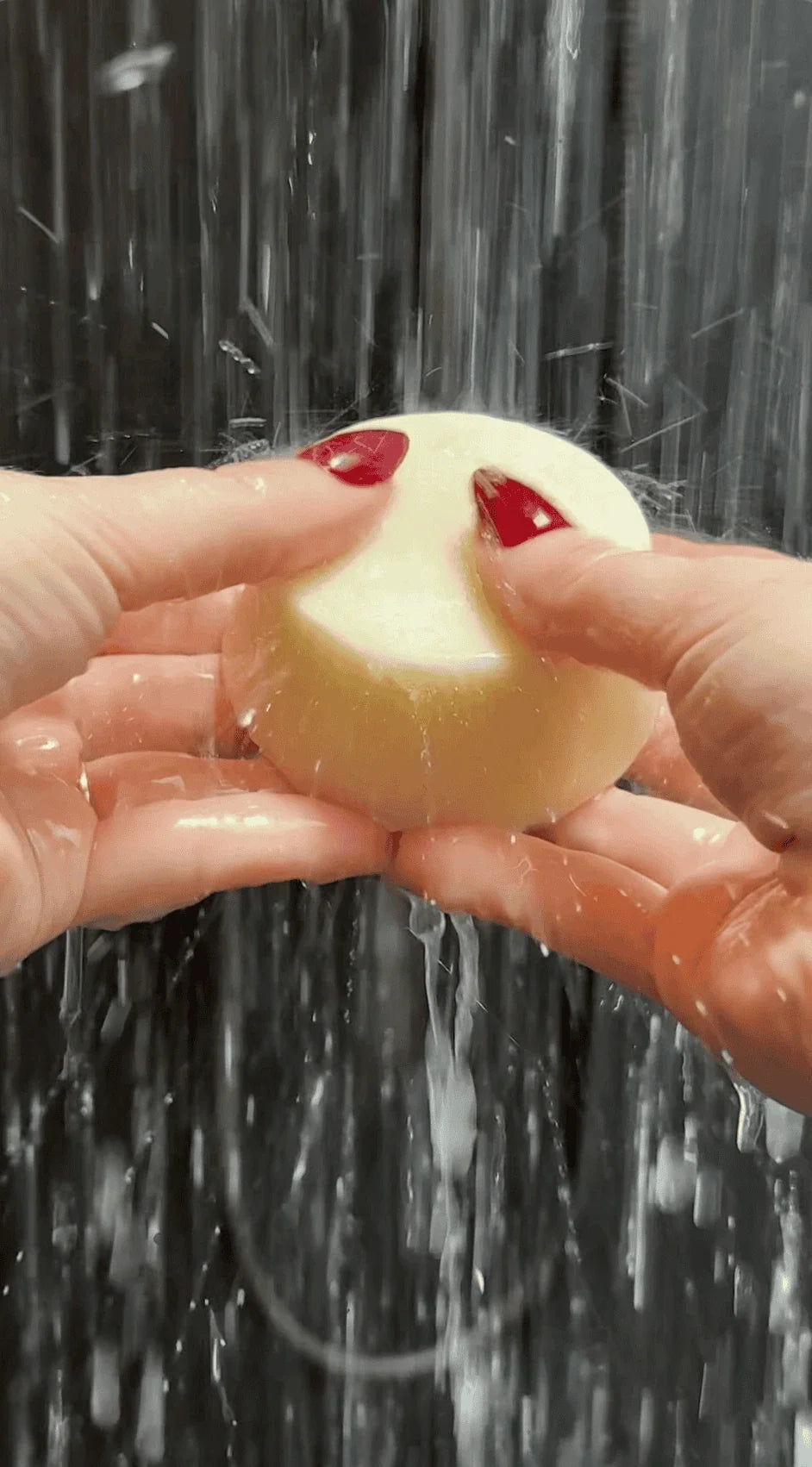 Hands holding a NaturalCare shampoo bar under running water