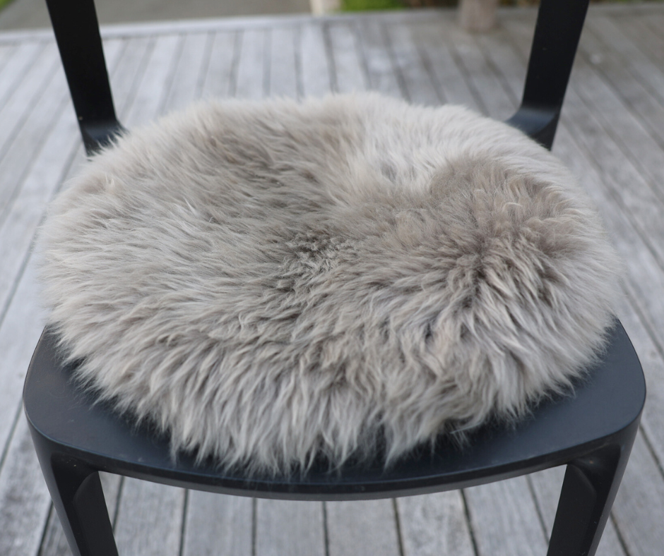 Grey round sheepskin seat pad on a black chair