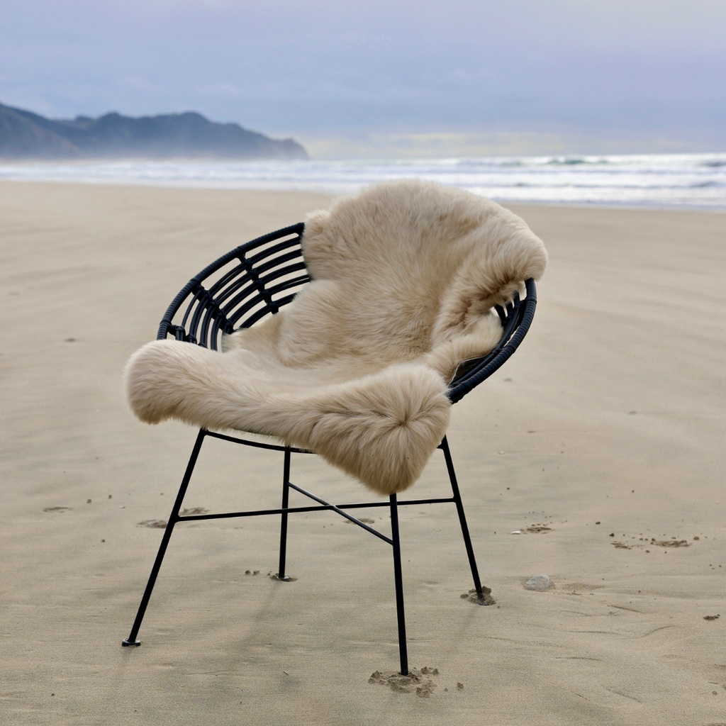 Sand single sheepskin rug over a chair on a beach