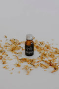 Subliminal essential oil blend in a small amber bottle by Bumble & Birdie, among dried petals