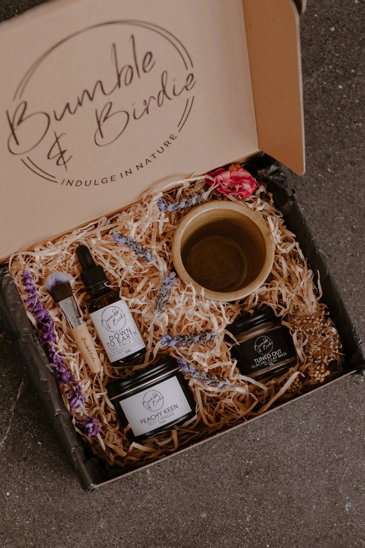 Down to Earth Ritual Set in an open Bumble & Birdie gift box with a face oil, clay mask, candle and clay bowl