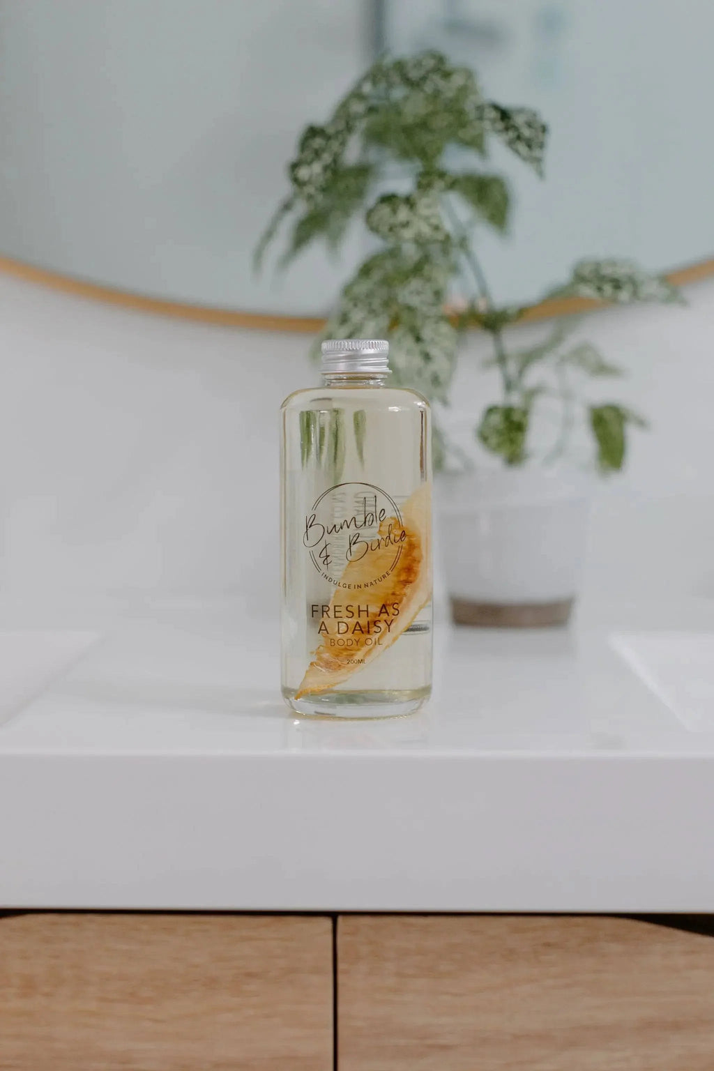 Fresh as a Daisy body oil bottle from the Winter Revival set on a bathroom vanity