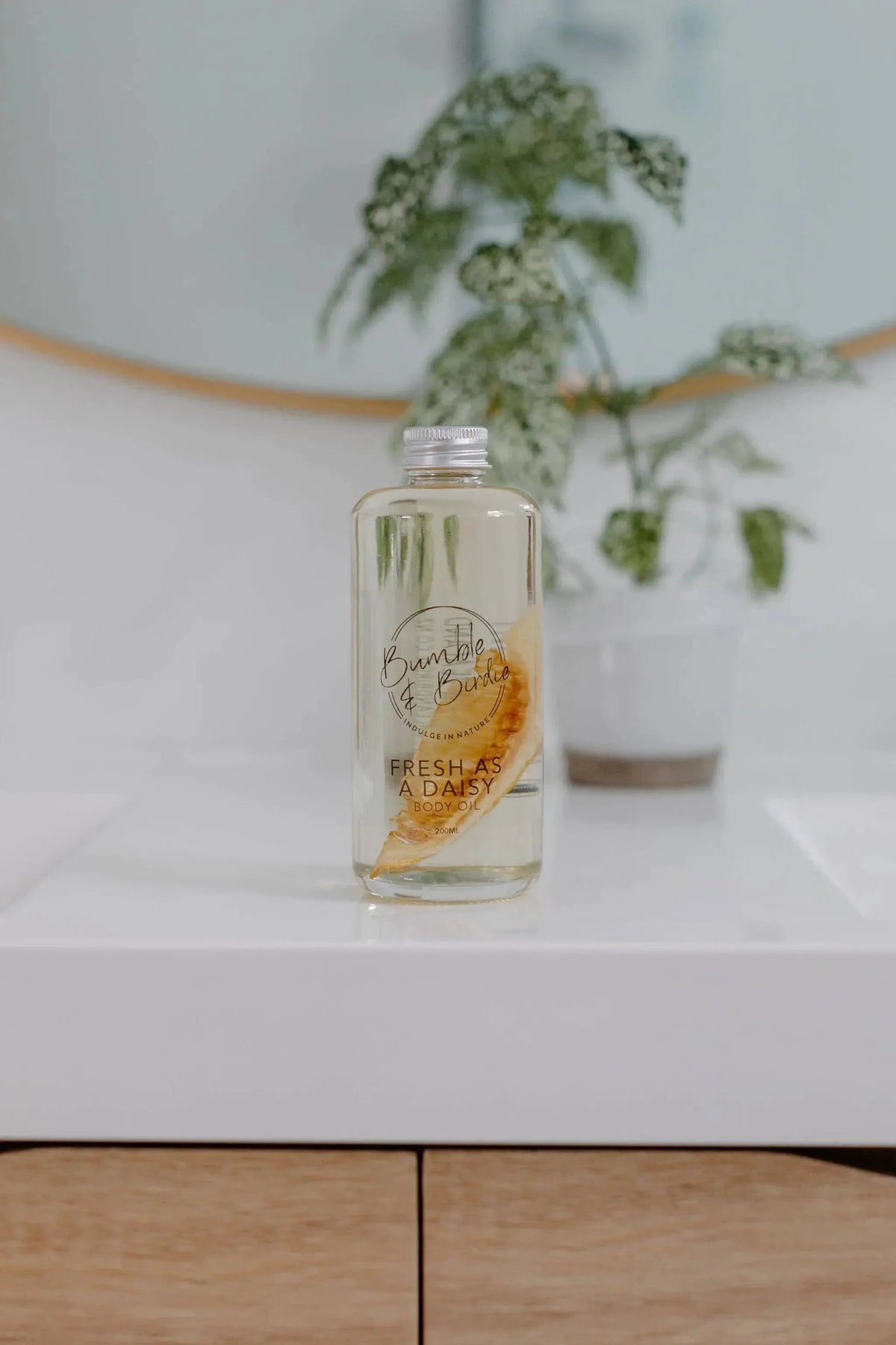 Fresh as a Daisy body oil bottle from the Winter Revival set on a bathroom vanity