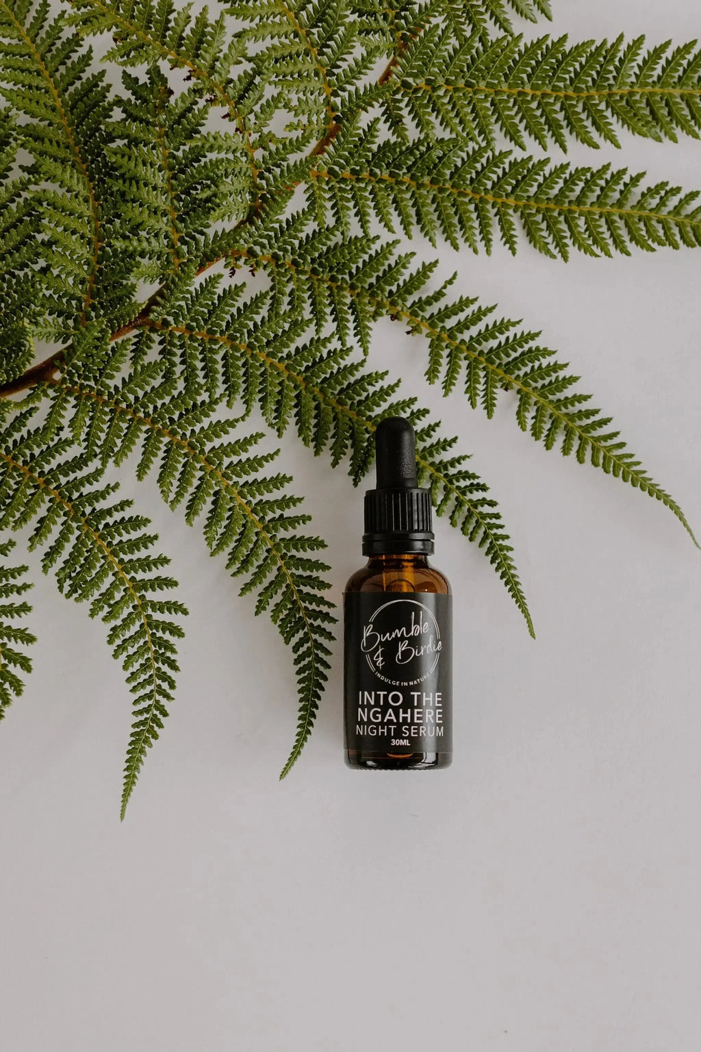 Into the Ngahere night serum dropper bottle from the Winter Revival set, with a fern frond