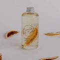 Fresh as a Daisy bath and body oil in a clear bottle by Bumble & Birdie, with dried citrus slices