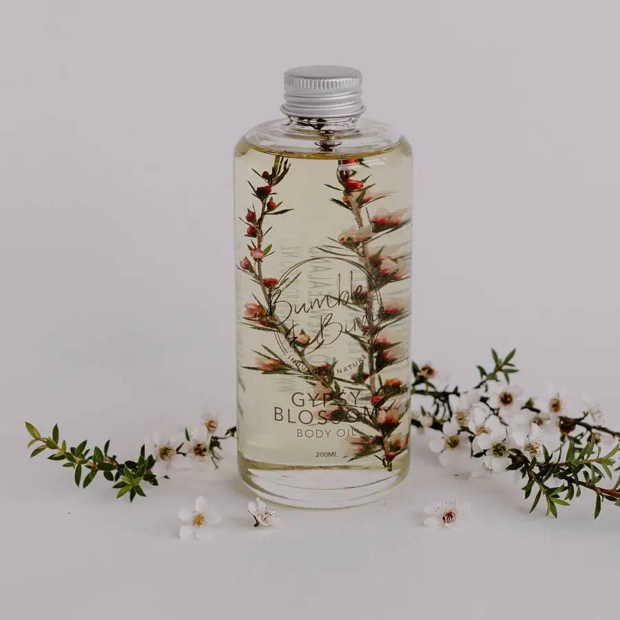 Gypsy Blossom body and shower oil in a clear bottle with a flowering sprig inside, by Bumble & Birdie