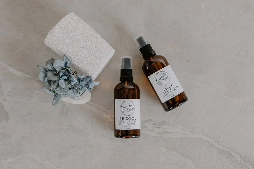 Two Be Cool facial mist spray bottles with a loofah and dried hydrangea