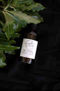 Be Cool facial mist in an amber spray bottle by Bumble & Birdie, on a dark background with leaves
