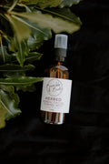Herbed facial toning mist in an amber spray bottle on a dark background with leaves