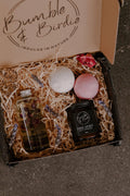 Kiss & Tell Gift Set in an open Bumble & Birdie box with a body oil, jar candle and two bath bombs