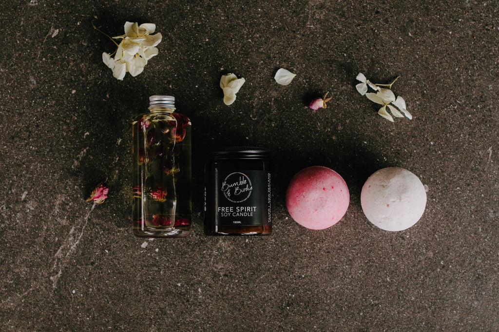 Kiss & Tell Gift Set laid out: Catching Feelings body oil, Nectar jar candle and two bath bombs