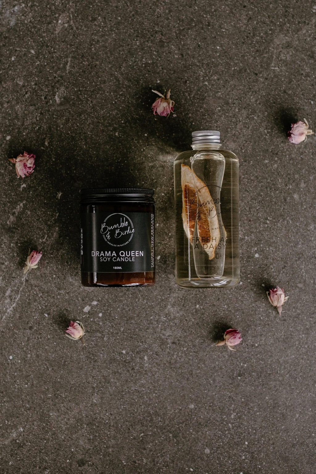Drama Queen jar candle and Fresh as a Daisy body oil from the Pick Me Up set, on a dark surface