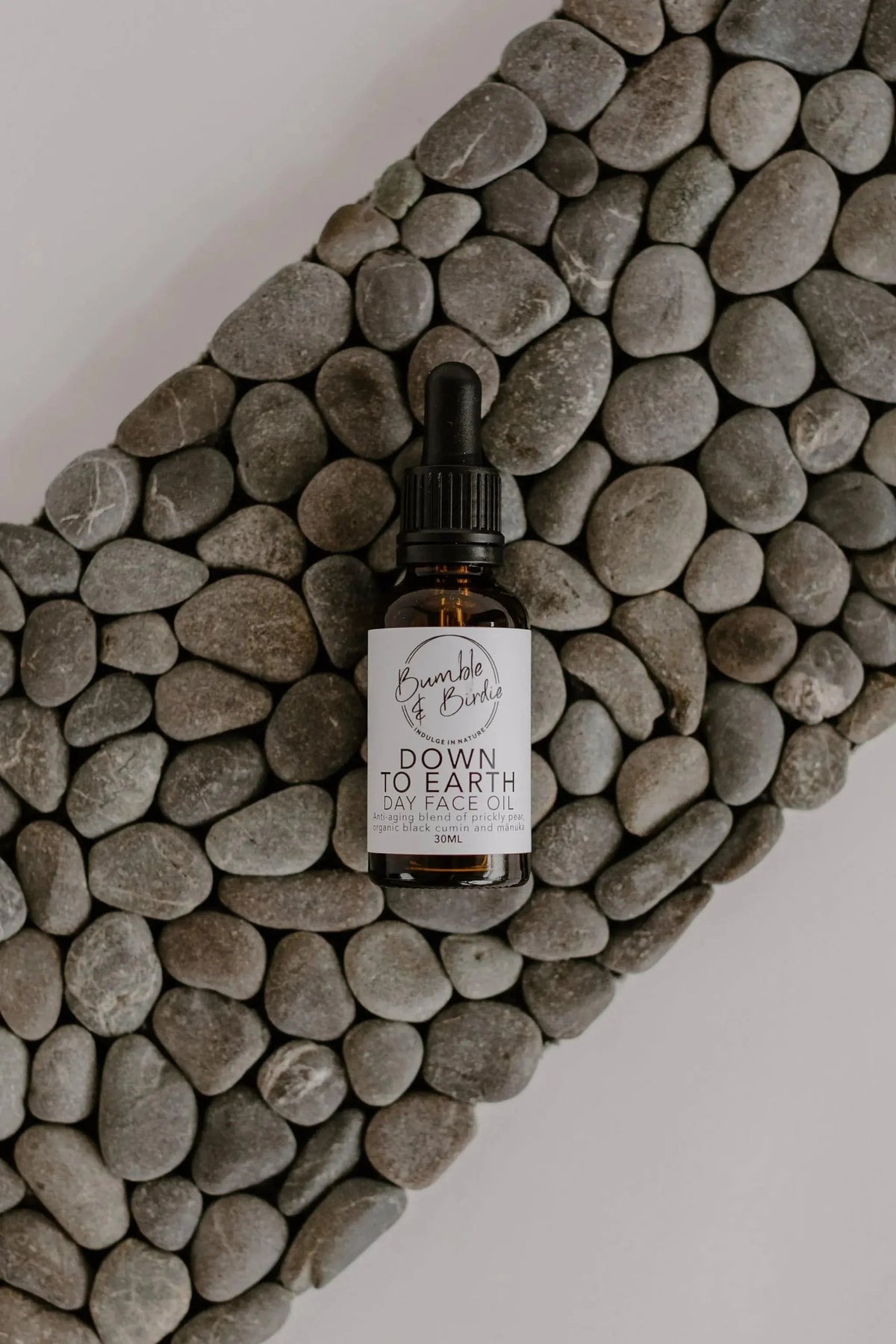 Down to Earth face oil dropper bottle on a pebble mat, a face oil option in the Powerhouse Ritual Set