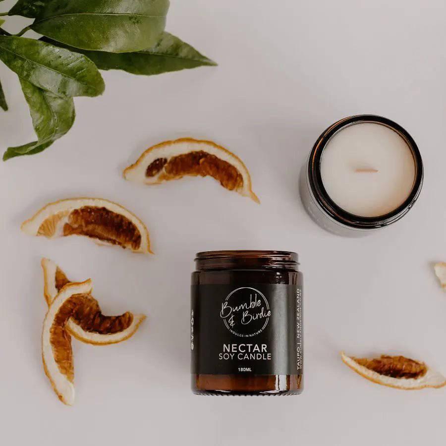 Nectar soy candle in an amber glass jar by Bumble & Birdie, with dried orange slices