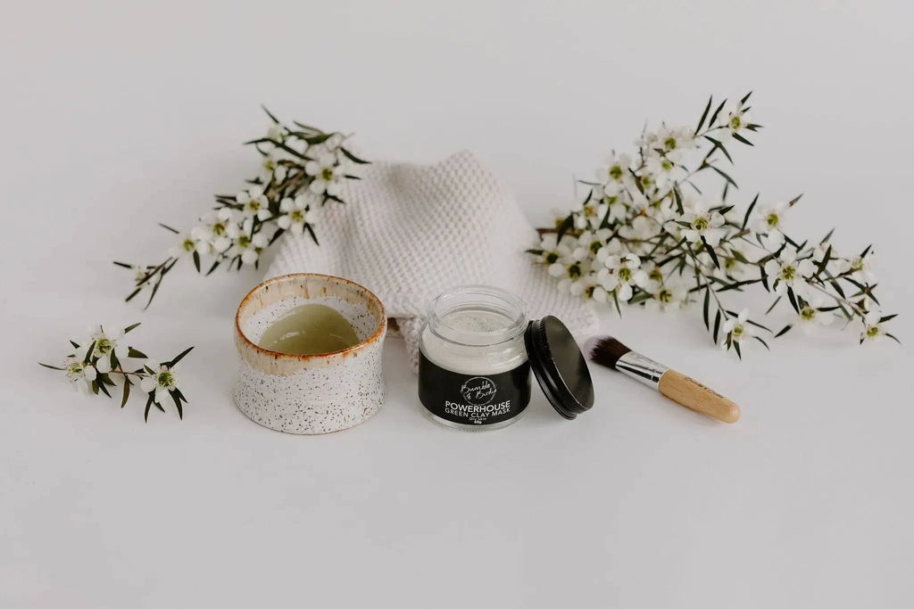 Clay Mask Ritual Set laid out with a clay pot of mixed mask, a mask jar and a brush among white flowers