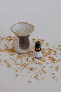 Infusion Aromatherapy Set: speckled clay oil diffuser with a bottle of essential oil among dried petals