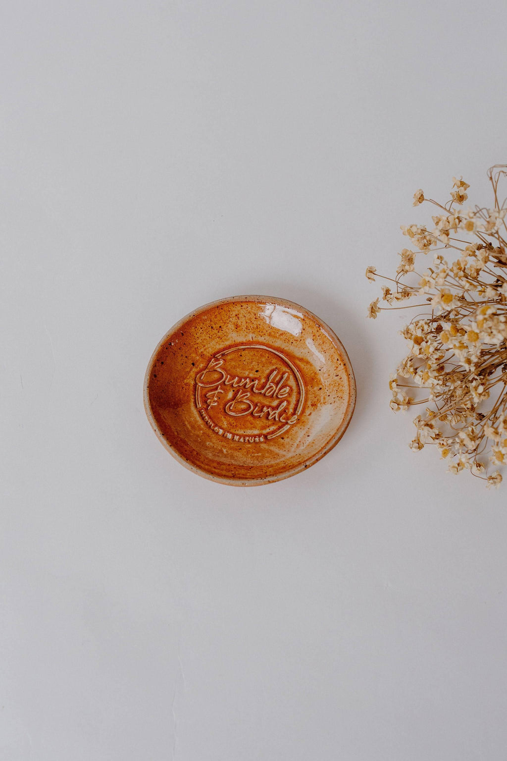 Earth Soap Sanctuary clay soap dish in a burnt orange glaze, with dried flowers