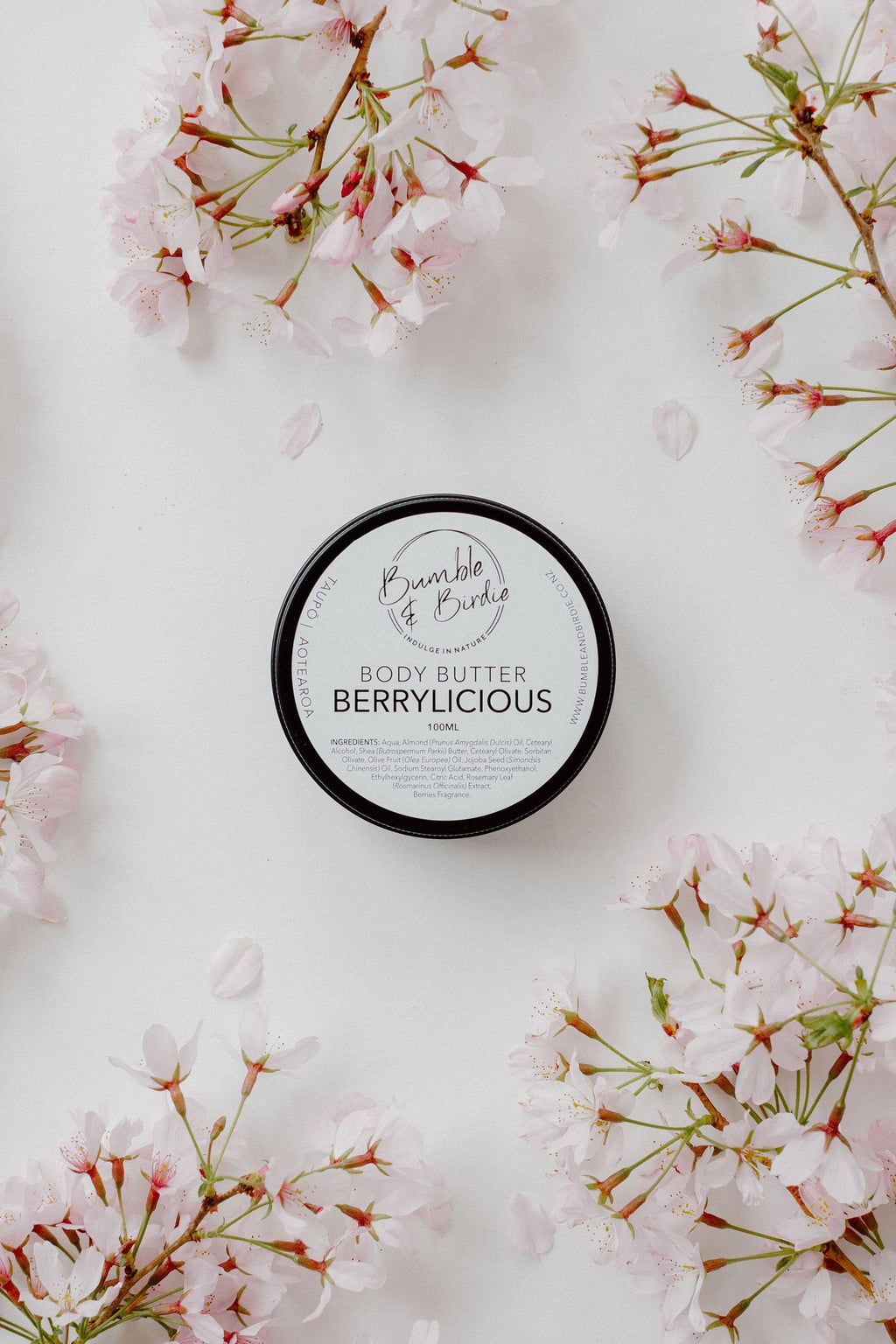 Tin of Berrylicious body butter by Bumble & Birdie among pink blossom