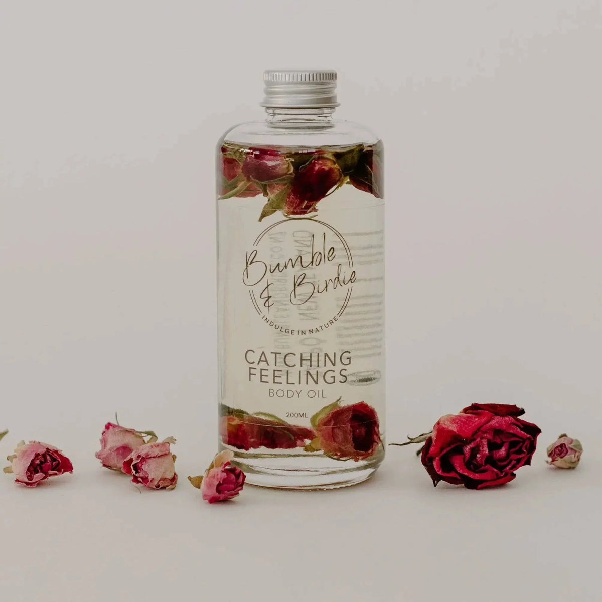 Catching Feelings body oil in a clear bottle with rose buds inside, by Bumble & Birdie, with roses