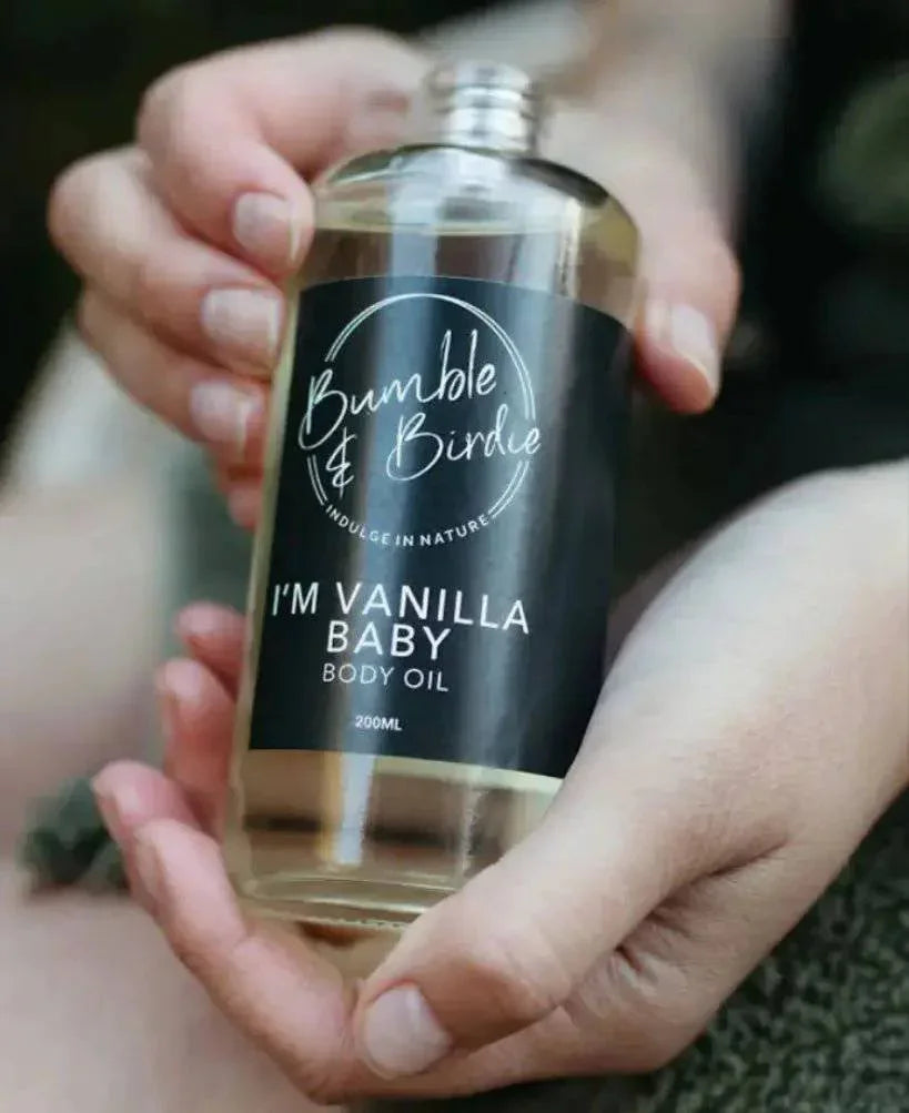 Hands holding a bottle of Im Vanilla Baby body oil by Bumble & Birdie