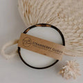 Strawberry Guava pure coconut candle in a coconut shell with a Bumble & Birdie label, on a woven fan