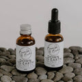 Down to Earth day face oil in a refill bottle and a dropper bottle by Bumble & Birdie, on grey pebbles