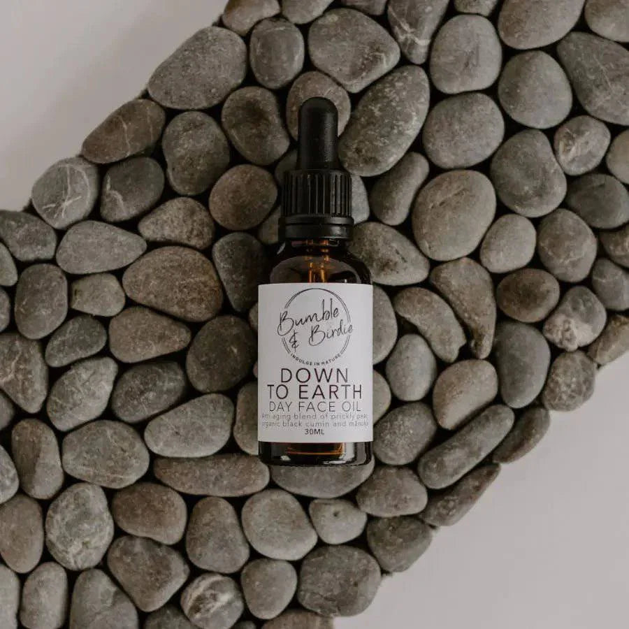 Down to Earth day face oil dropper bottle lying on a pebble mat