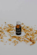 Chakras Relaxant essential oil blend in a small amber bottle by Bumble & Birdie, among dried petals