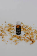 Let Go essential oil blend in a small amber bottle by Bumble & Birdie, among dried petals
