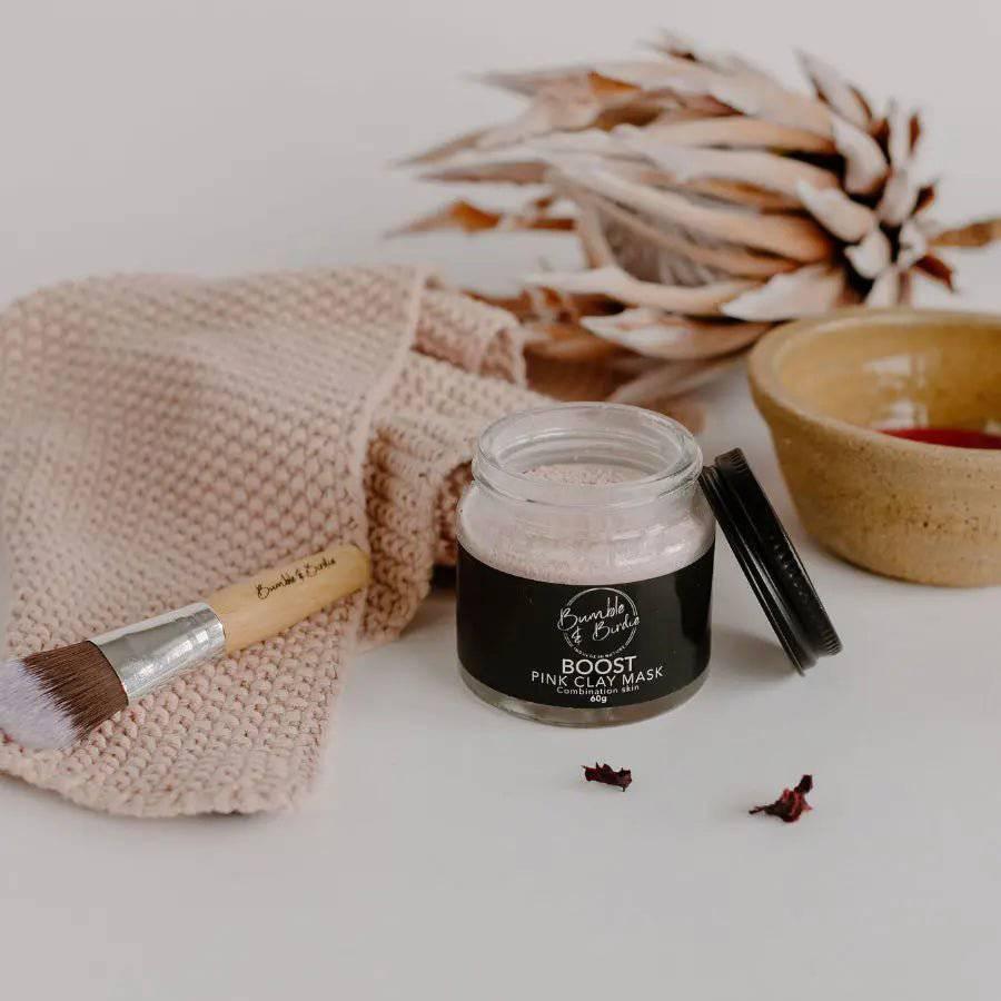 Boost Pink Clay Mask jar with a mask brush, a knitted cloth and a clay bowl