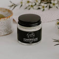 Jar of Powerhouse Green Clay Mask by Bumble & Birdie beside a speckled clay bowl and white flowers